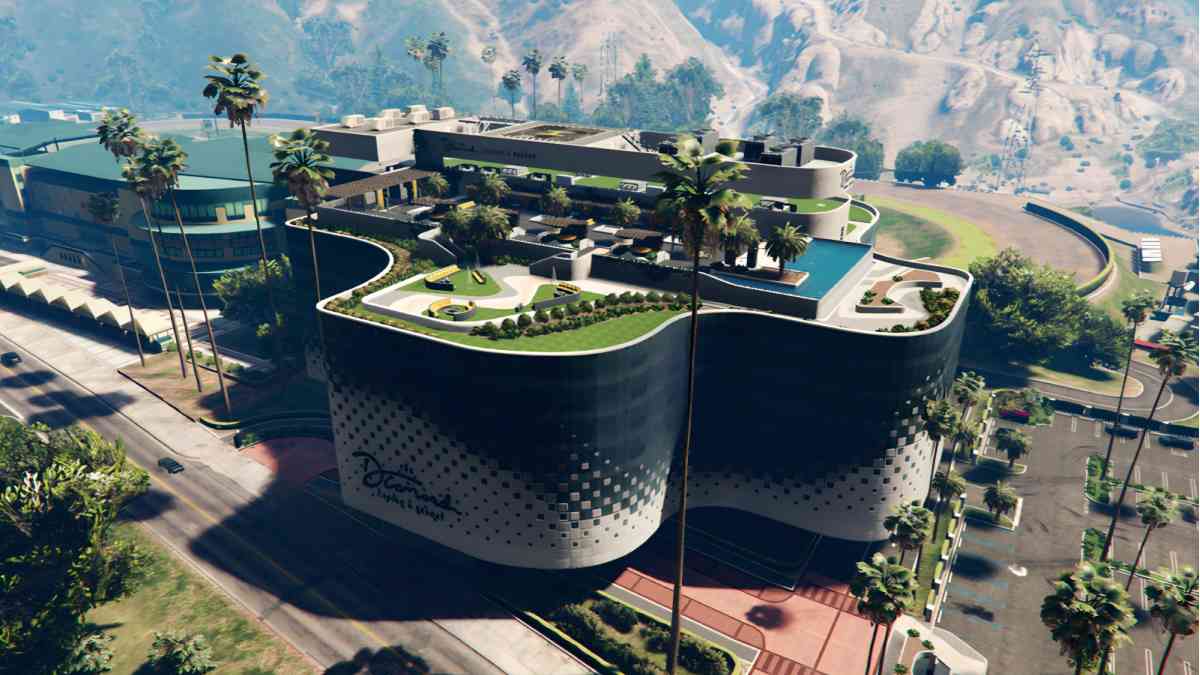 A modern, curvy hotel with lush rooftop gardens, surrounded by palm trees and set against a mountainous backdrop.
