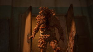 A massive infected creature emerges from a doorway in The Last of Us Part 1